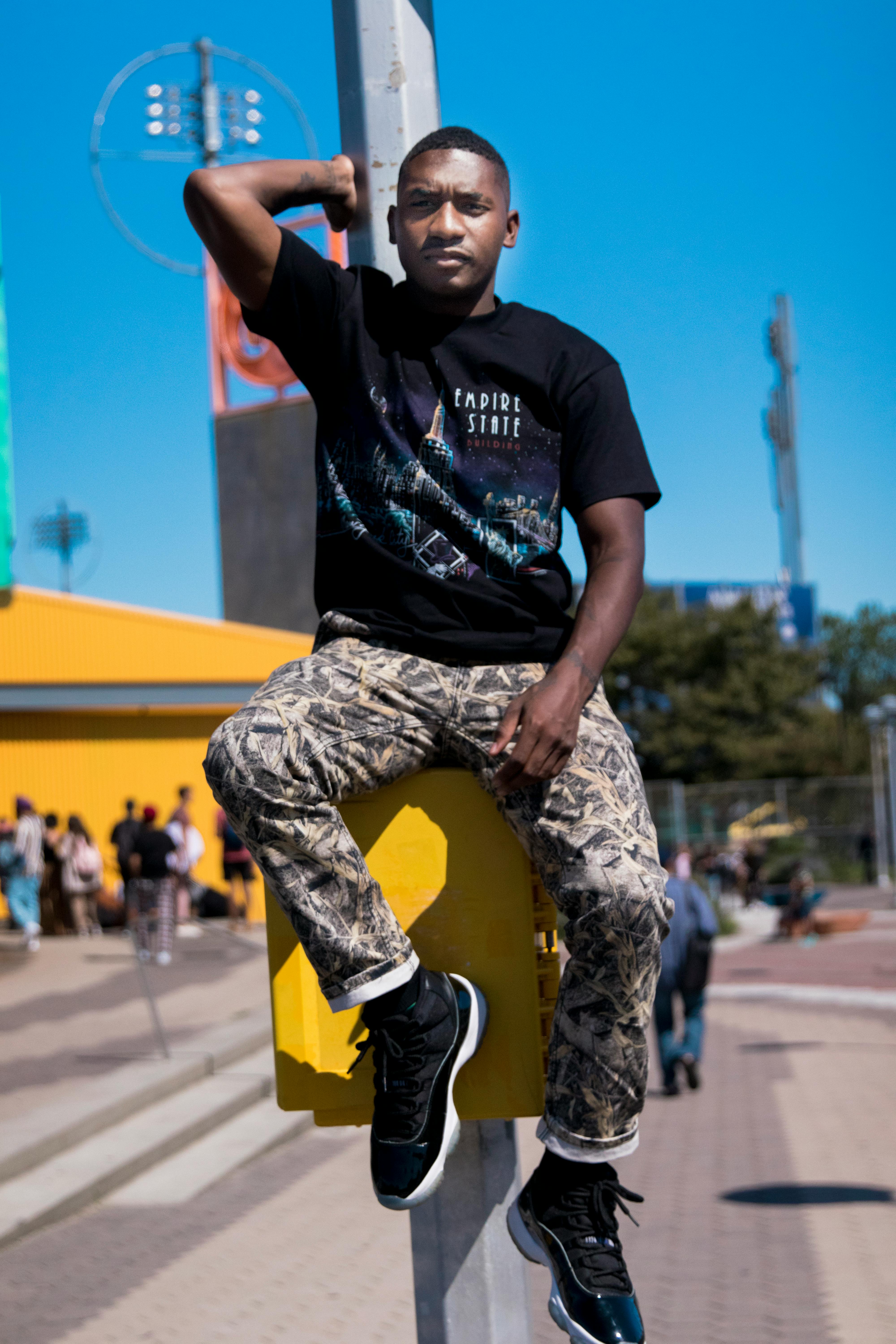 Stylish young man in casual wear posing on a sunny day in an urban park setting.
