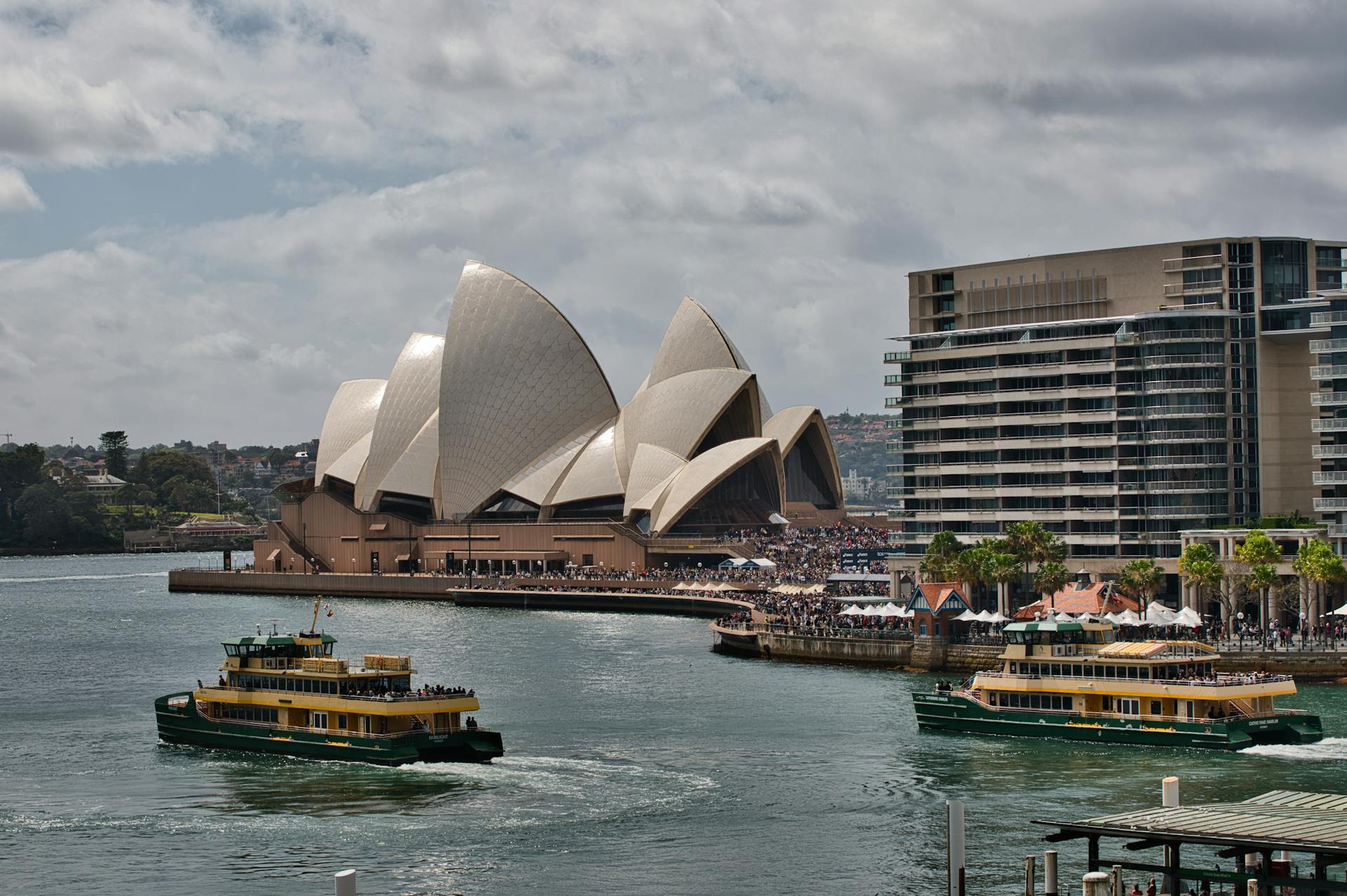 View of the famous Sydney Opera House and ferries navigating the bustling Sydney Harbour.