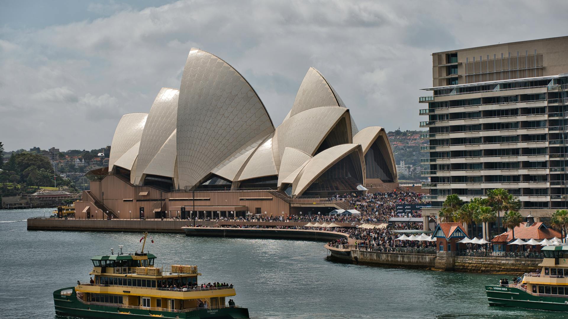 A vibrant scene at Sydney Opera House with a ferry passing by, showcasing Sydney's lively waterfront.