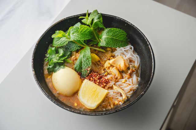A flavorful Asian noodle bowl with fresh herbs, citrus, and a savory broth.