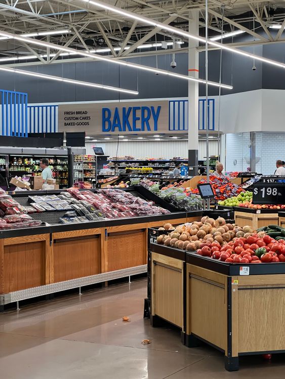 Produce section of a modern supermarket with fresh fruit displays and bakery signage