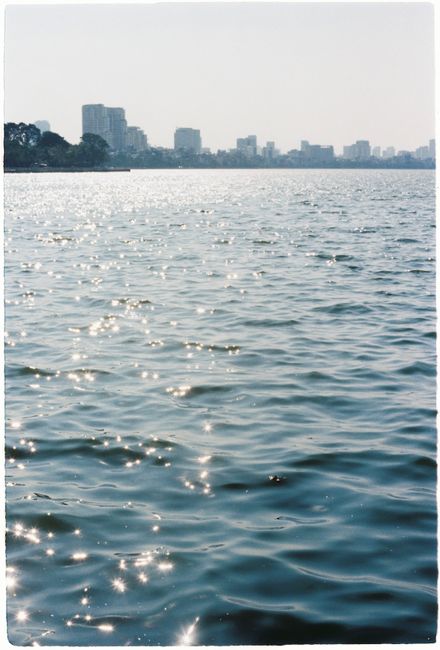 Glistening water with a distant city skyline under a bright sky, creating a tranquil urban scene.
