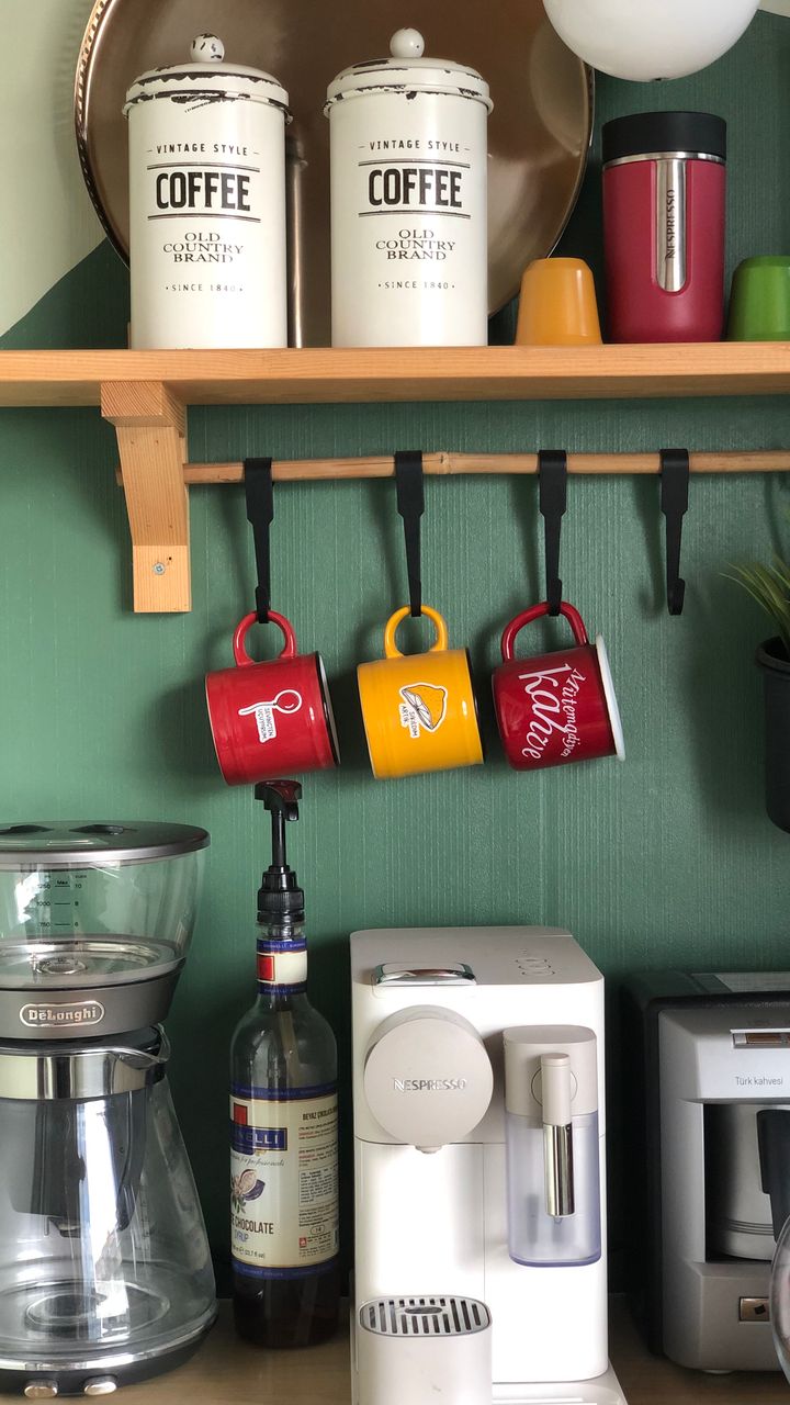 Mismatched vintage ceramic canisters in earthy tones displayed on a boho coffee bar shelf for storage