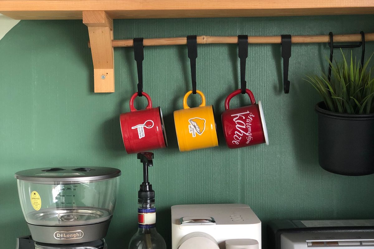Small coffee station with wall shelves, hanging mugs and coffee canisters