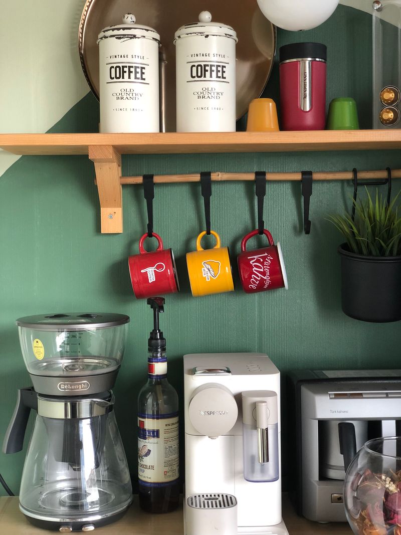 Colorful coffee mugs hanging on a wall shelf at a cozy home coffee station