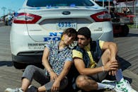 阳光明媚的户外，一对夫妇随意与警车合影