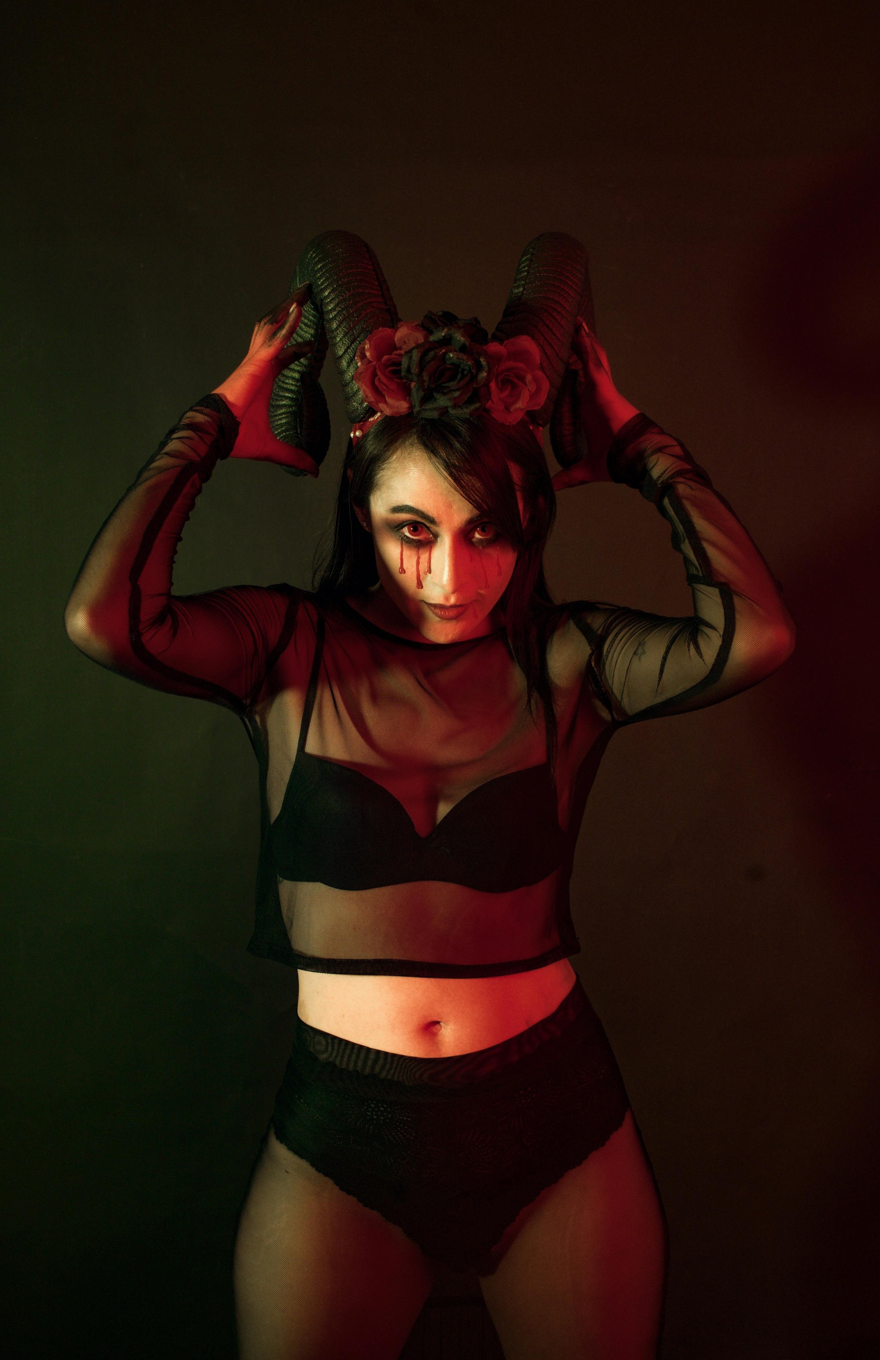grátis Uma mulher vestindo uma fantasia escura de Halloween com chifres de diabo e maquiagem dramática. Foto profissional