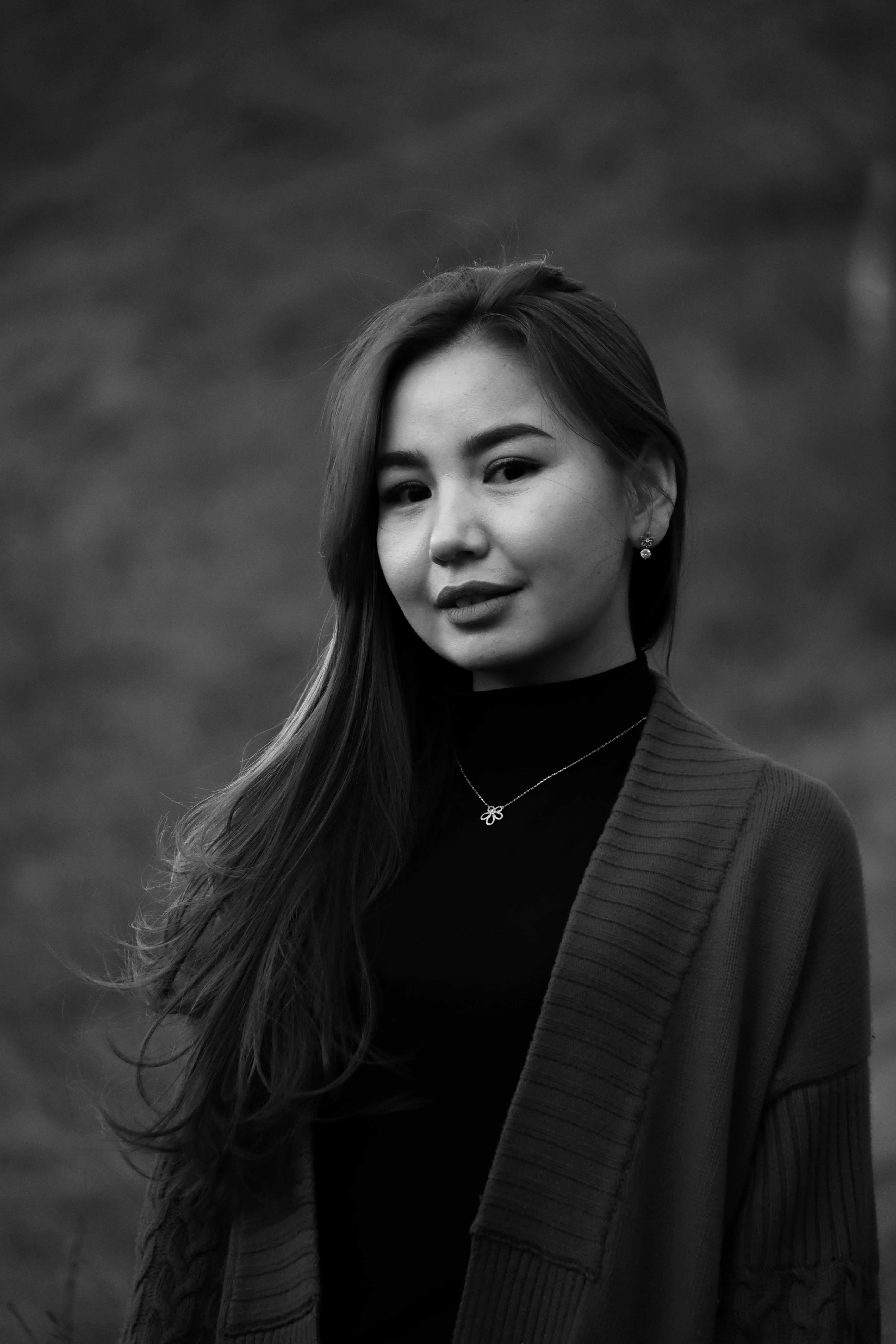 Black and white portrait of a young woman with long hair, wearing a necklace.