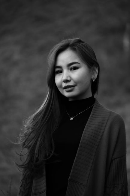 Black and white portrait of a young woman with long hair, wearing a necklace.