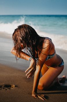 Young woman with wet hair on a sunny beach day by the ocean.