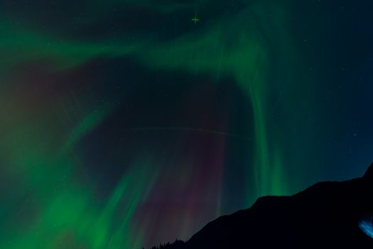 Captivating display of Northern Lights over a silhouetted mountain range at night.