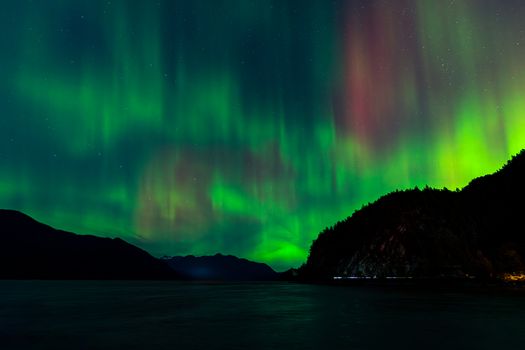 Breathtaking view of Northern Lights dancing over mountains and water.
