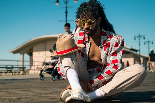 Man in Red and Gray Dress Shirt Sitting on Ground