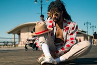 一位时尚男士戴着太阳镜和帽子，坐在木板路上