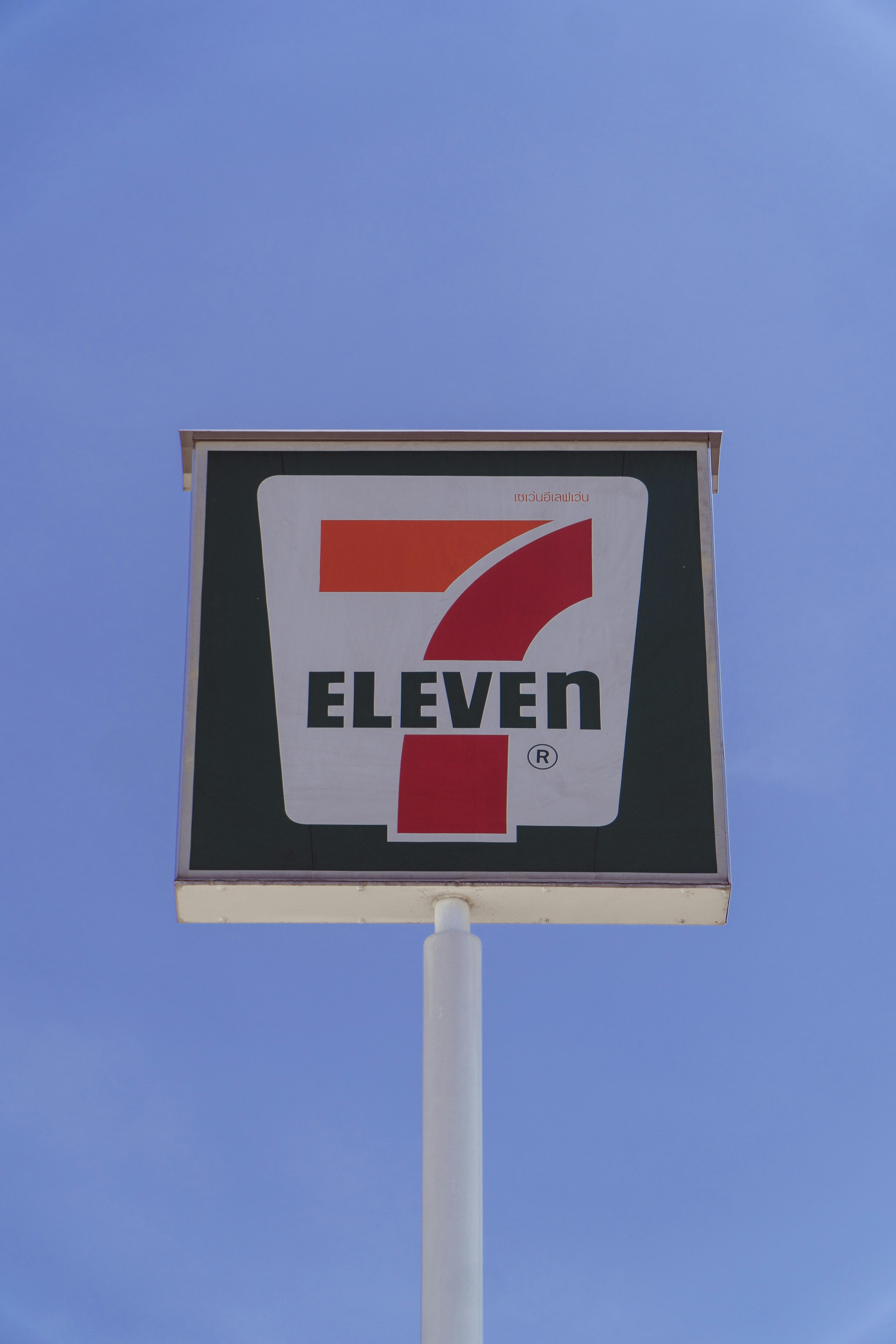 Photo of a 7-Eleven store sign against a bright blue sky, symbolizing convenience.