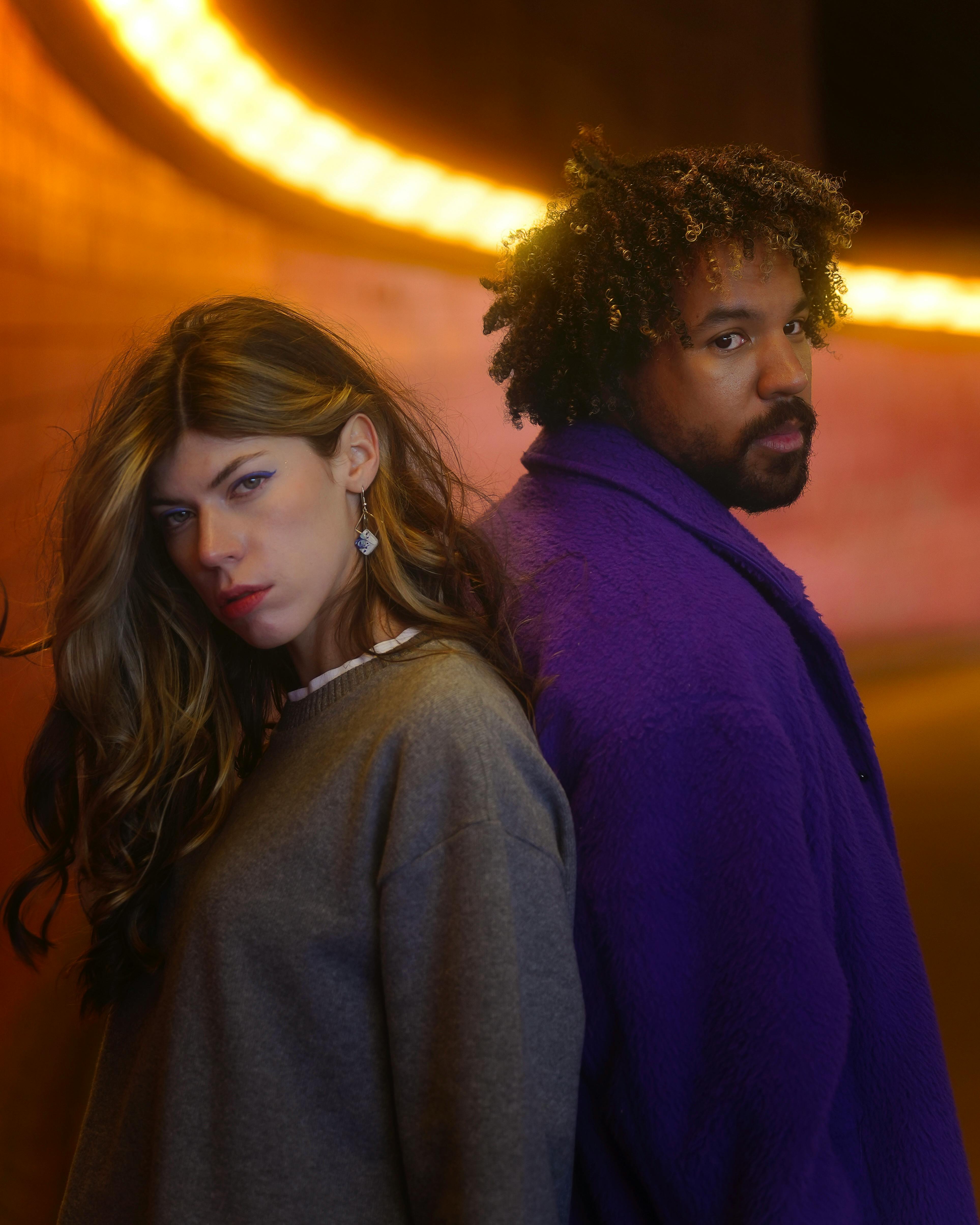 Free Chic portrait of two individuals in vibrant fashion under neon lights in Berlin. Stock Photo