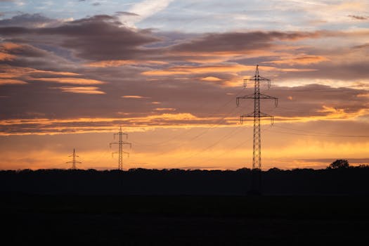 Dramatic sunset over Austrian landscape featuring silhouetted power lines and vibrant sky colors.