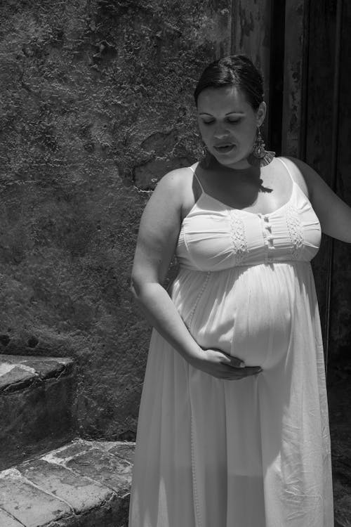 Fotografía En Escala De Grises De Una Mujer Embarazada Sosteniendo Su Panza