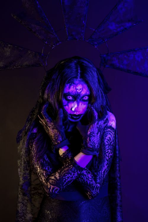 Free Dark Gothic woman with intense expression under vivid purple lighting in eerie setting. Stock Photo