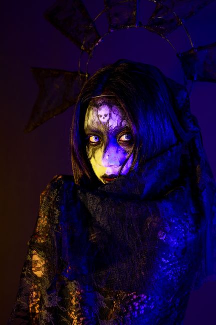 Haunting gothic portrait featuring eerie makeup and dark lighting, creating a mysterious atmosphere.