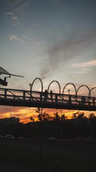 A striking silhouette of people on a bridge at sunset, with a colorful sky.