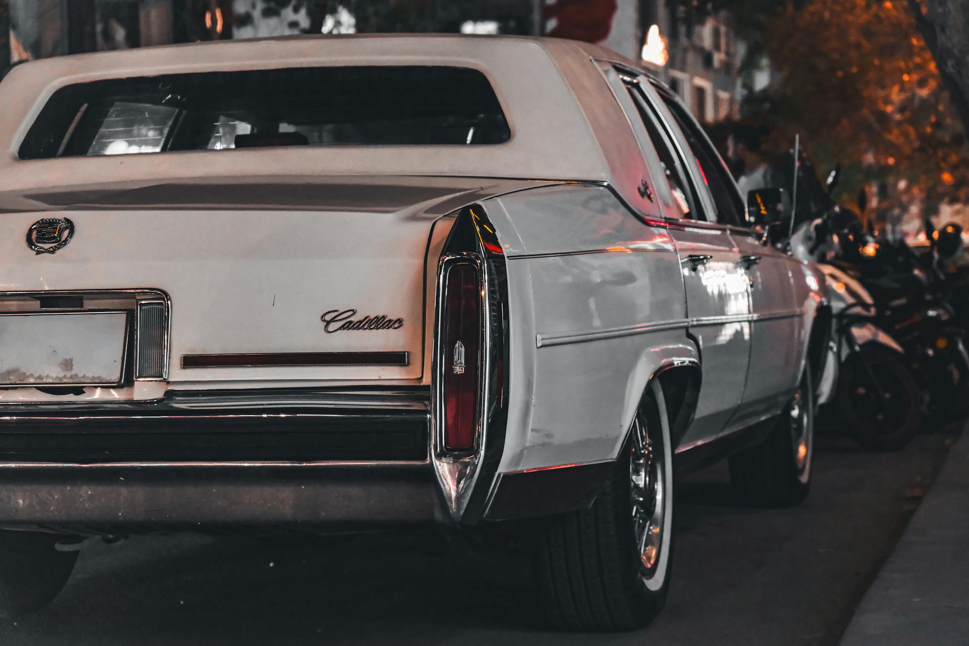 Rear view of a vintage Cadillac parked on a city street at night, showcasing its elegant design.