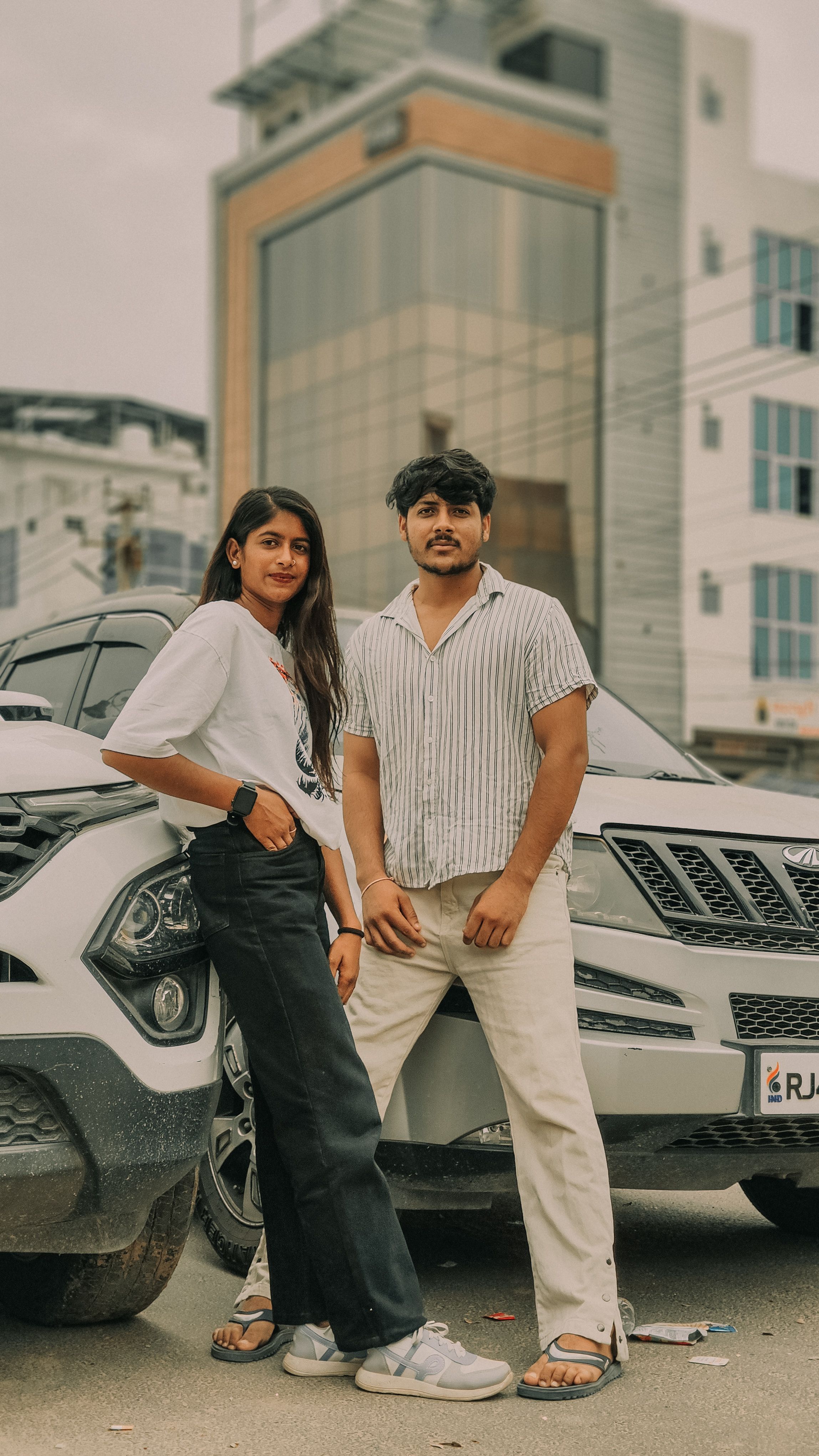 Stylish young adults posing confidently with a modern SUV in an urban locale, showcasing urban lifestyle and fashion.
