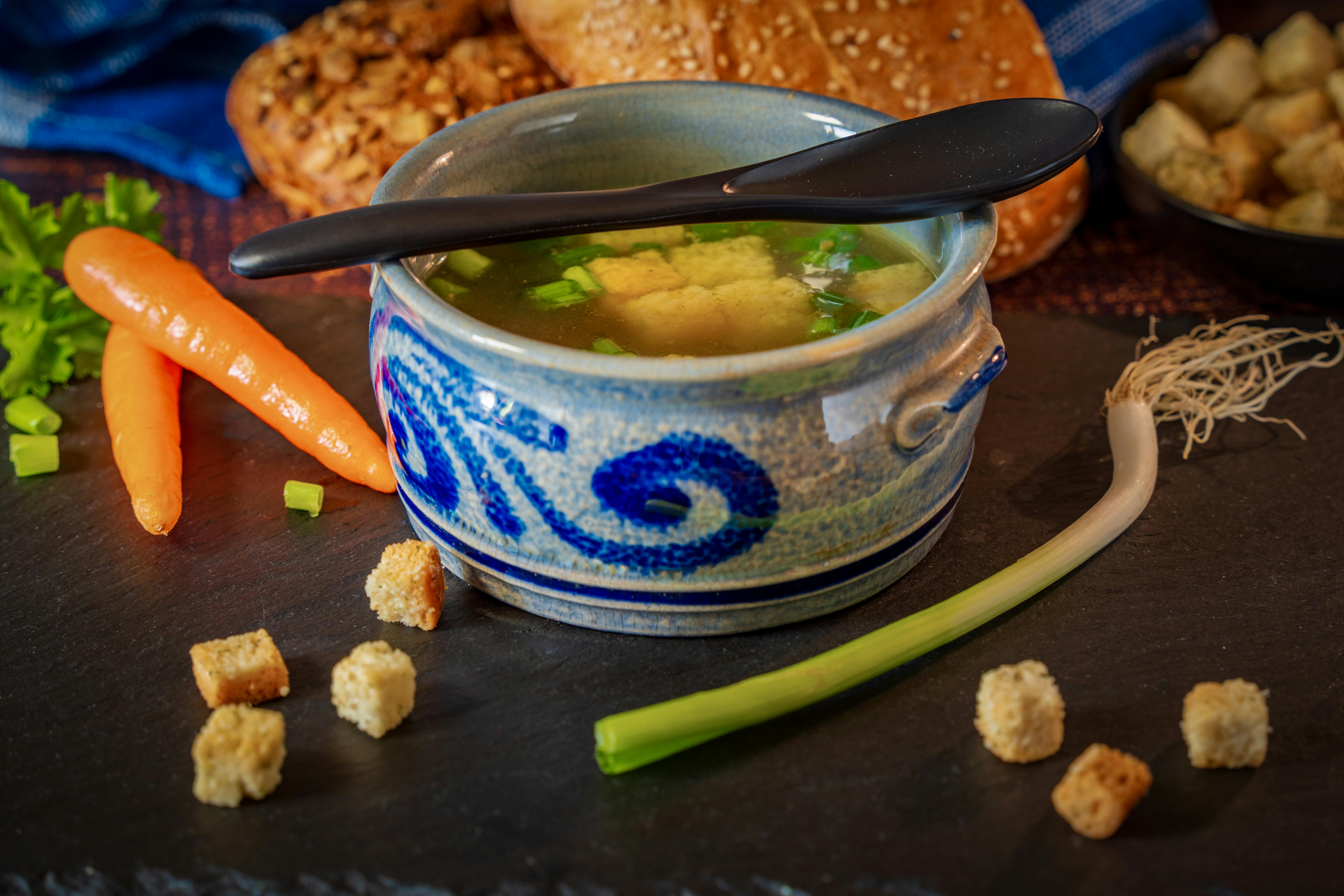 A comforting bowl of vegetable broth with fresh carrots, leeks, and croutons, perfect for a cozy meal.