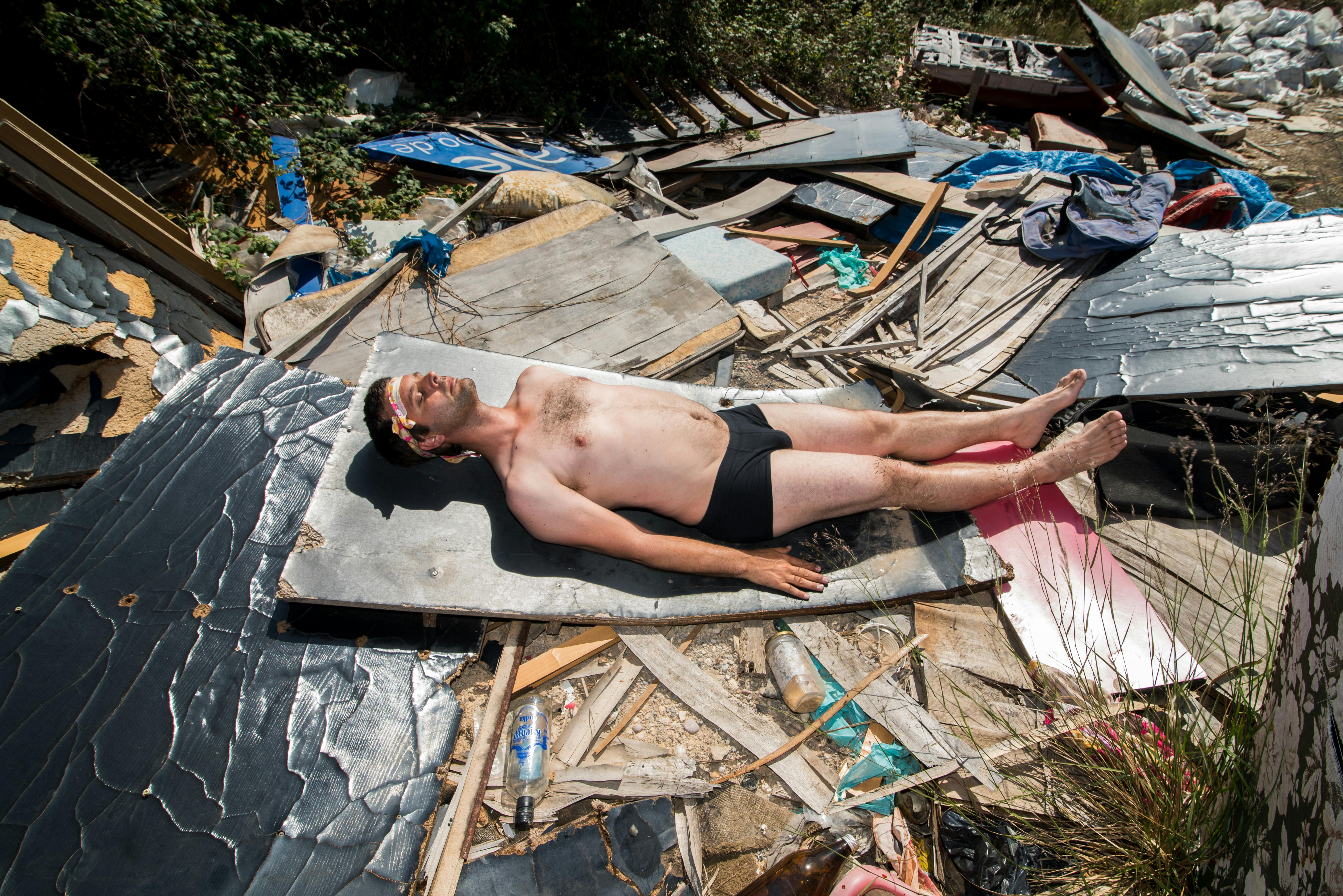 man sunbathing amidst urban debris outdoors