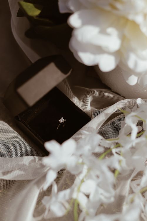 Free A beautiful diamond engagement ring in an open velvet box, surrounded by delicate flowers - a perfect symbol of love. Stock Photo