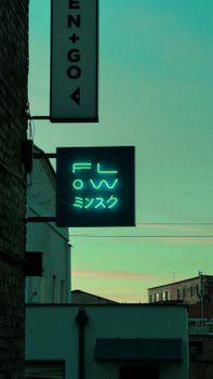 A vibrant neon sign illuminates an urban alleyway with a modern facade.