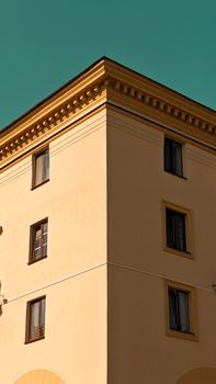 A yellow building with decorative edges photographed against a vibrant teal sky.