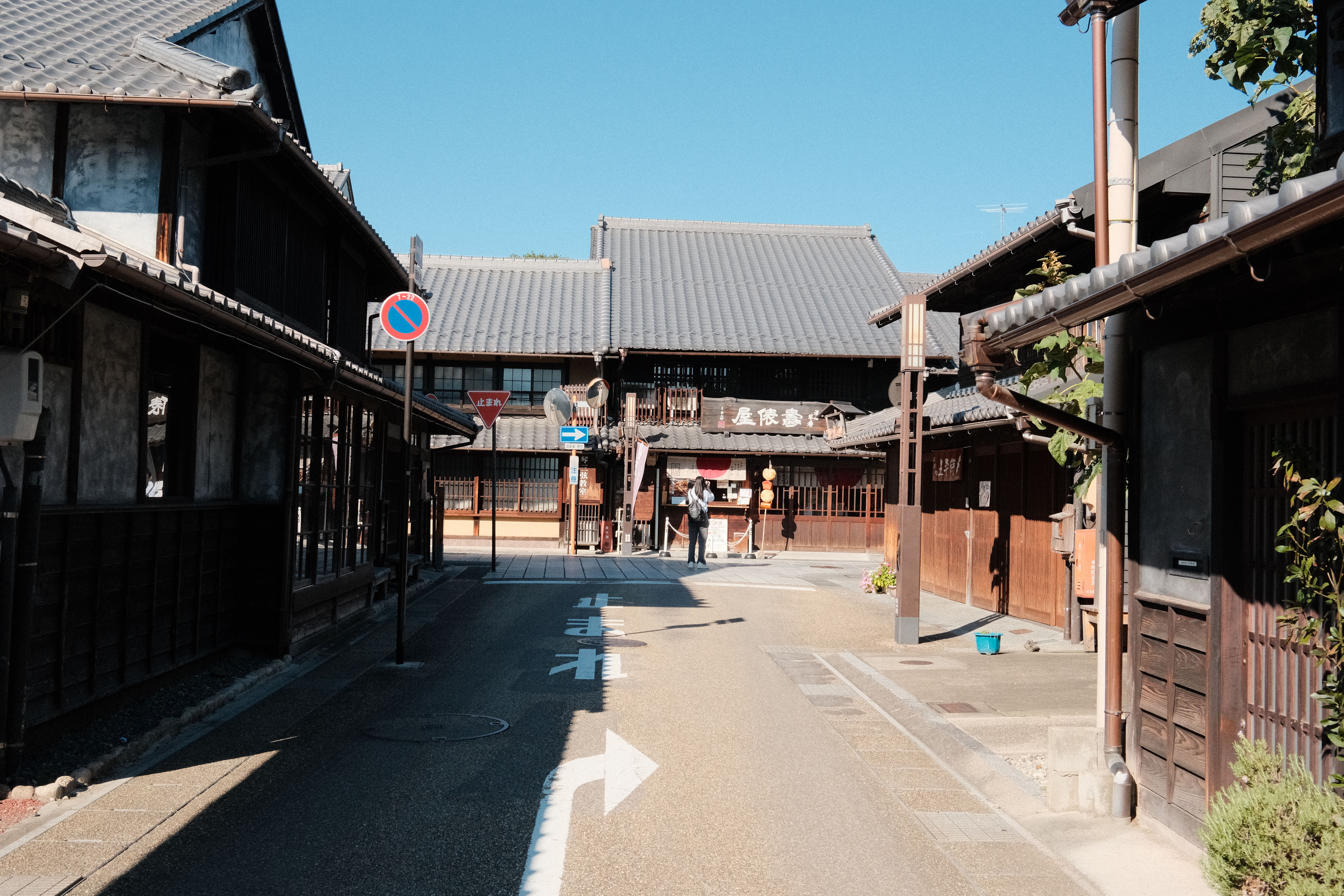 a quiet street in a traditional Okinawan village, a person walking in comfortable sandals