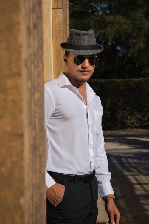 Free Confident man in hat and sunglasses posing outdoors on a sunny day. Stock Photo