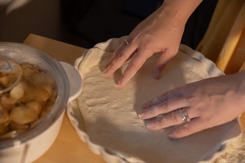 Free Hands shaping dough in a pie dish next to apple filling, ready to bake. Stock Photo