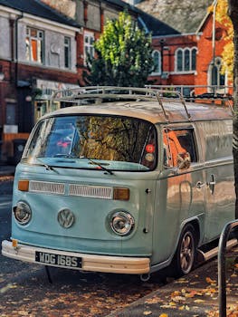 Classic VW camper van parked on a leaf-strewn street capturing autumn vibes