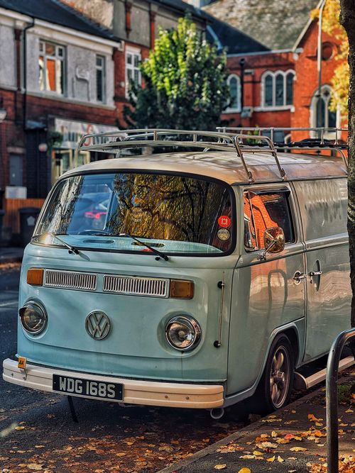 Free Classic VW camper van parked on a leaf-strewn street capturing autumn vibes Stock Photo
