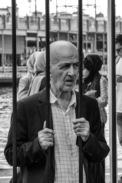 Free Black and white photo of an elderly man holding bars with a thoughtful expression. Stock Photo
