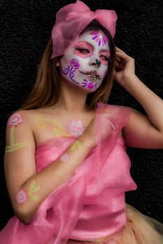 Vibrant portrait of a woman with artistic Day of the Dead makeup and pink tulle dress.