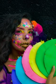 Colorful Day of the Dead face painting with neon hues and cultural decorations.