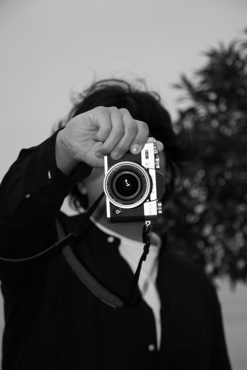 Free Monochrome portrait of a person holding a vintage camera, creating an artistic mood. Stock Photo