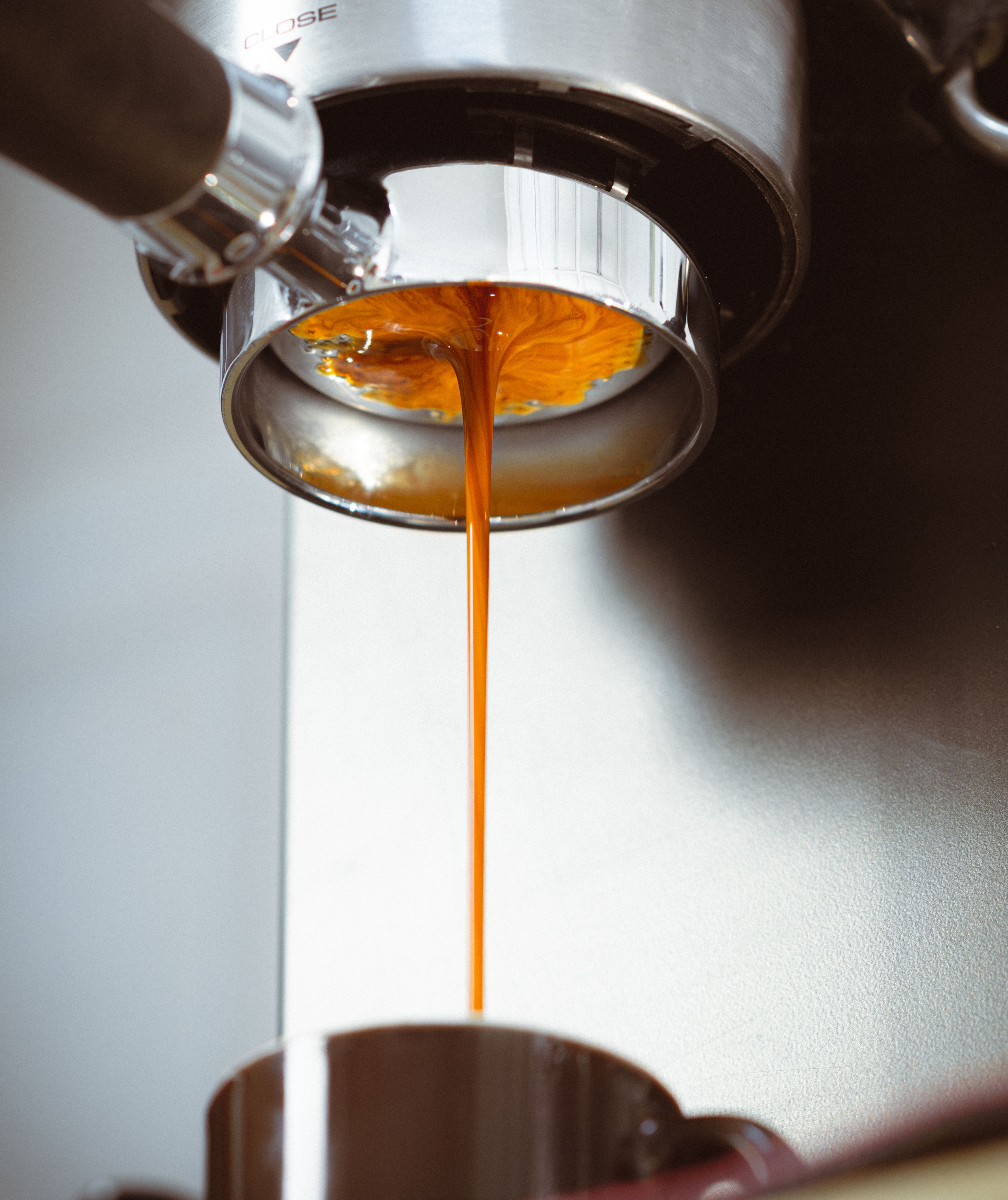 Espresso pouring from a portafilter into a cup, showing crema and the brewing process.