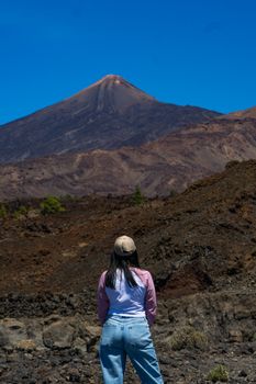 A woman gazes at the stunning volcanic terrain under clear blue skies in Tenerife.