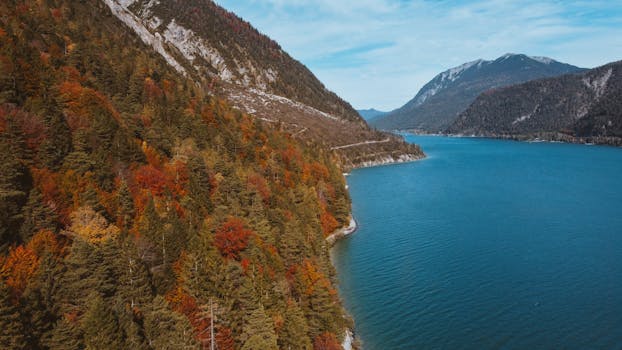 A breathtaking panorama of Achensee Lake surrounded by autumn foliage and mountains in Tirol, Austria.