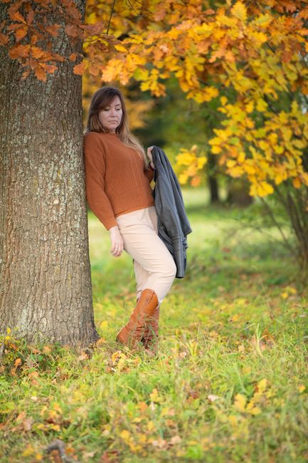 Fall color pairing inspiration: rust knit and cream trousers with a gray jacket in autumn foliage