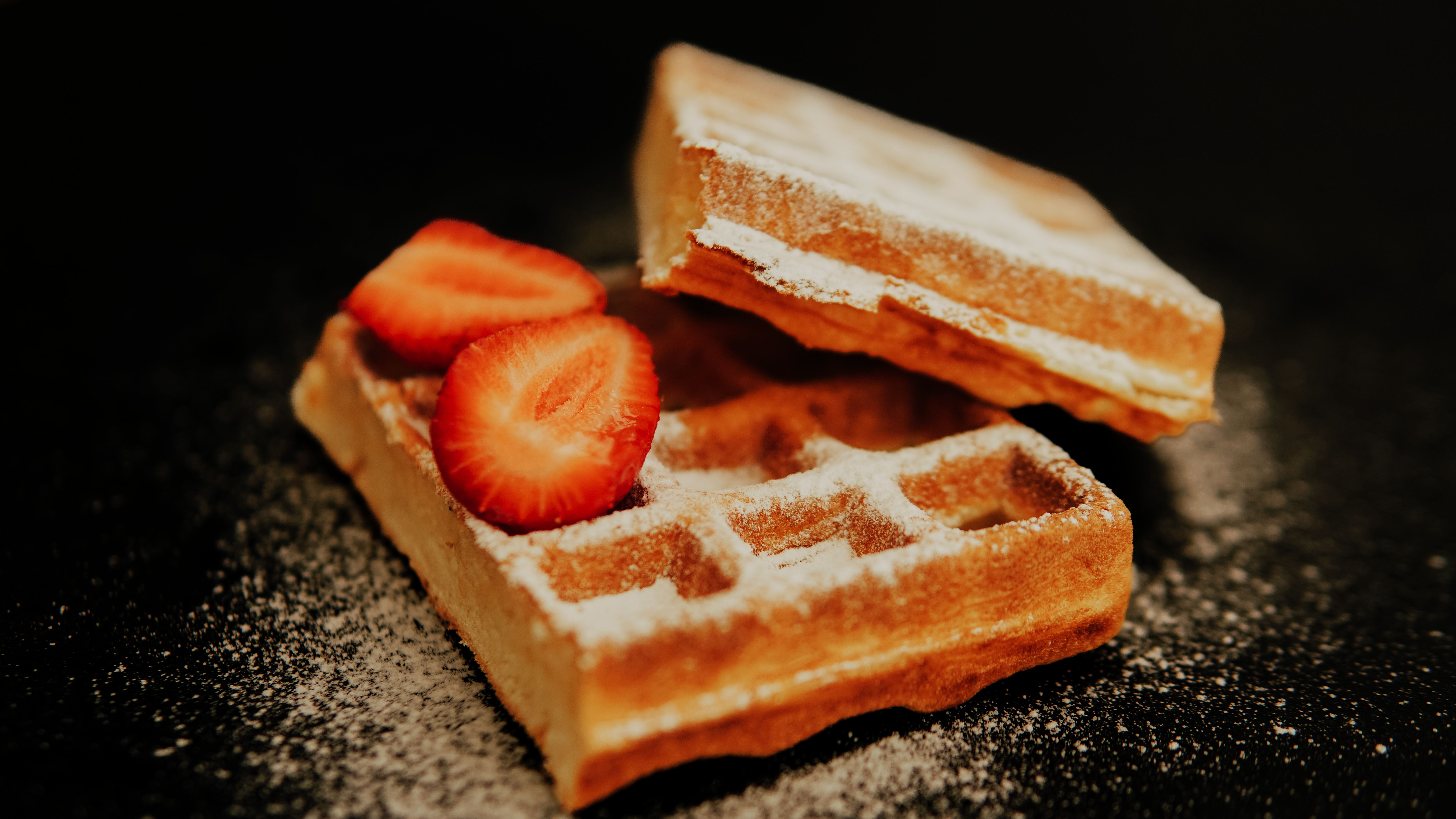 Golden brown waffles topped with fresh strawberries and sprinkled with sugar.
