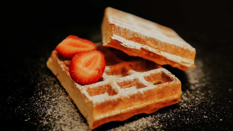 Golden brown waffles topped with fresh strawberries and sprinkled with sugar.