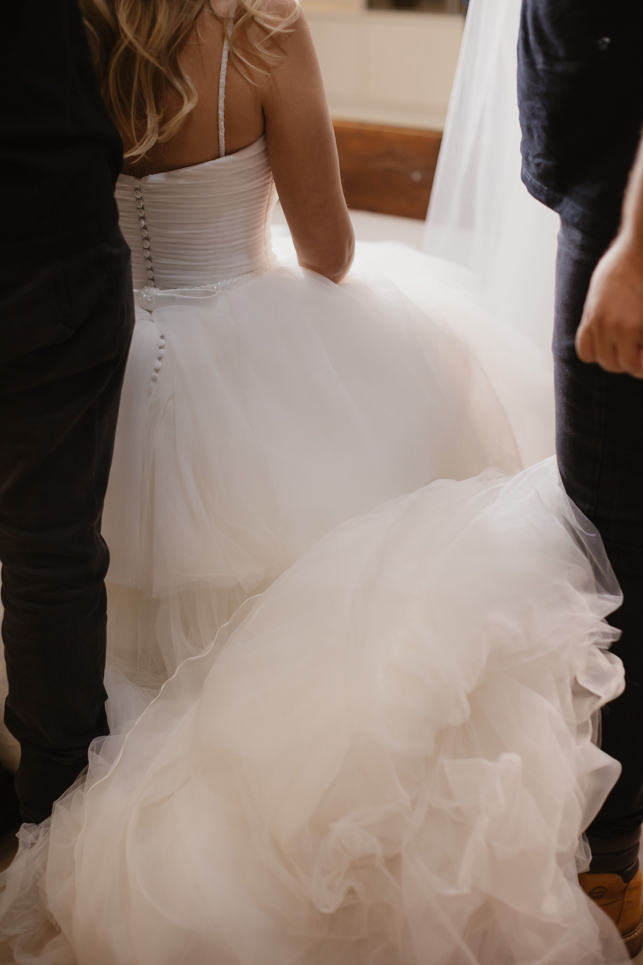 Beautiful bride in flowing dress captured from behind, preparing for her big day.