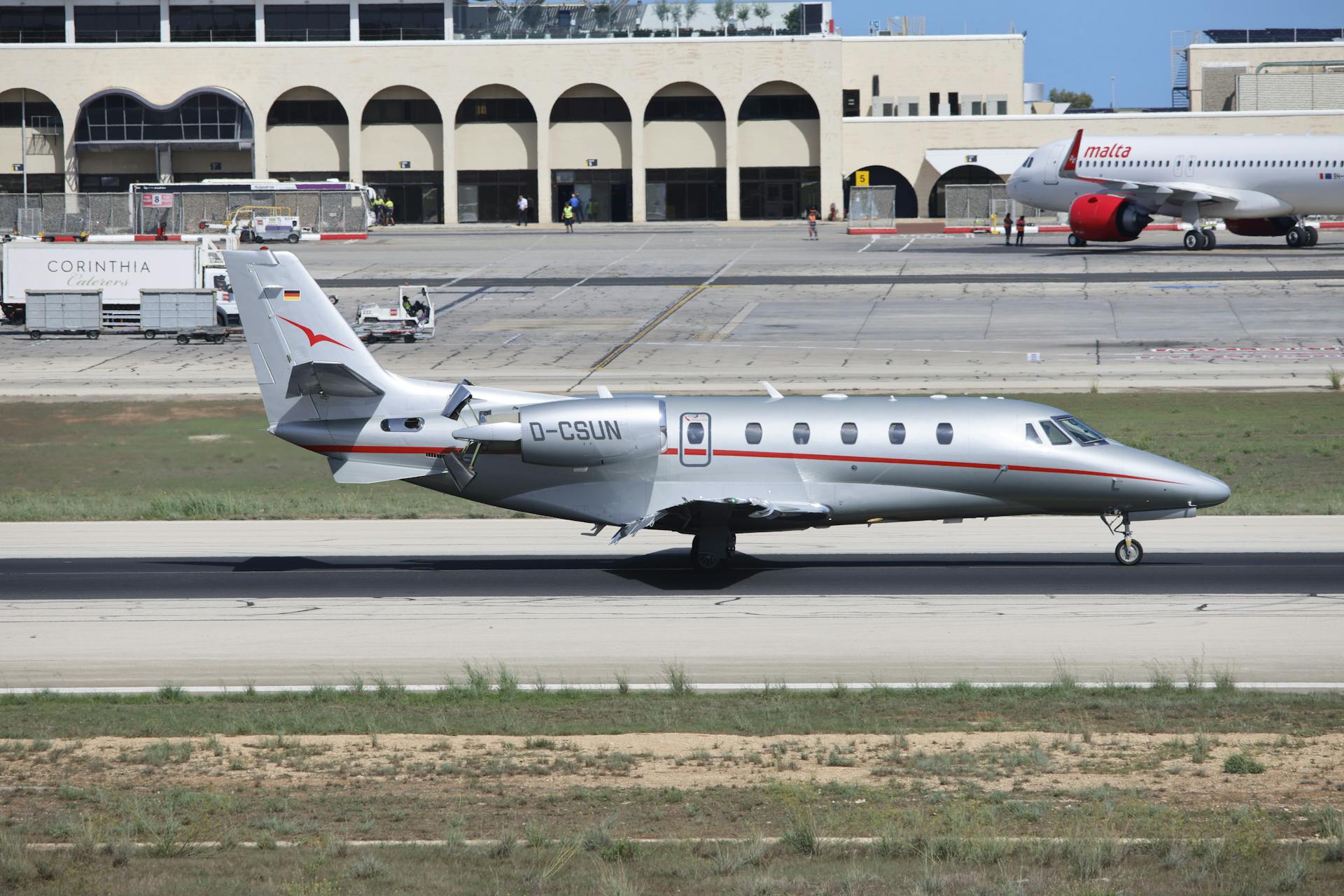 Private jet on runway at Malta's international airport under clear skies.