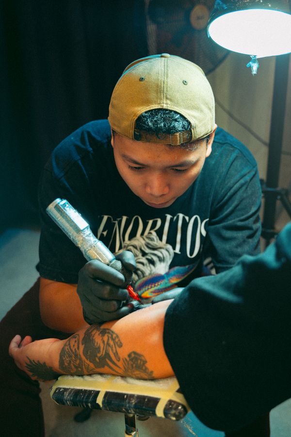 Artista tatuando braço